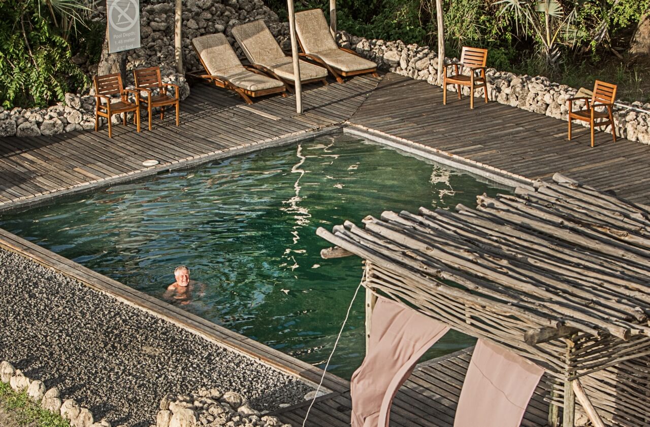 Großer Pool mit Sonnenliegen und Unterstand.