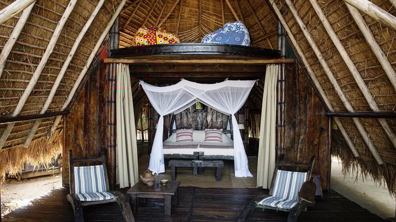 Himmelbett in einer Lodge mit hohem Dach aus Natirmaterialien.