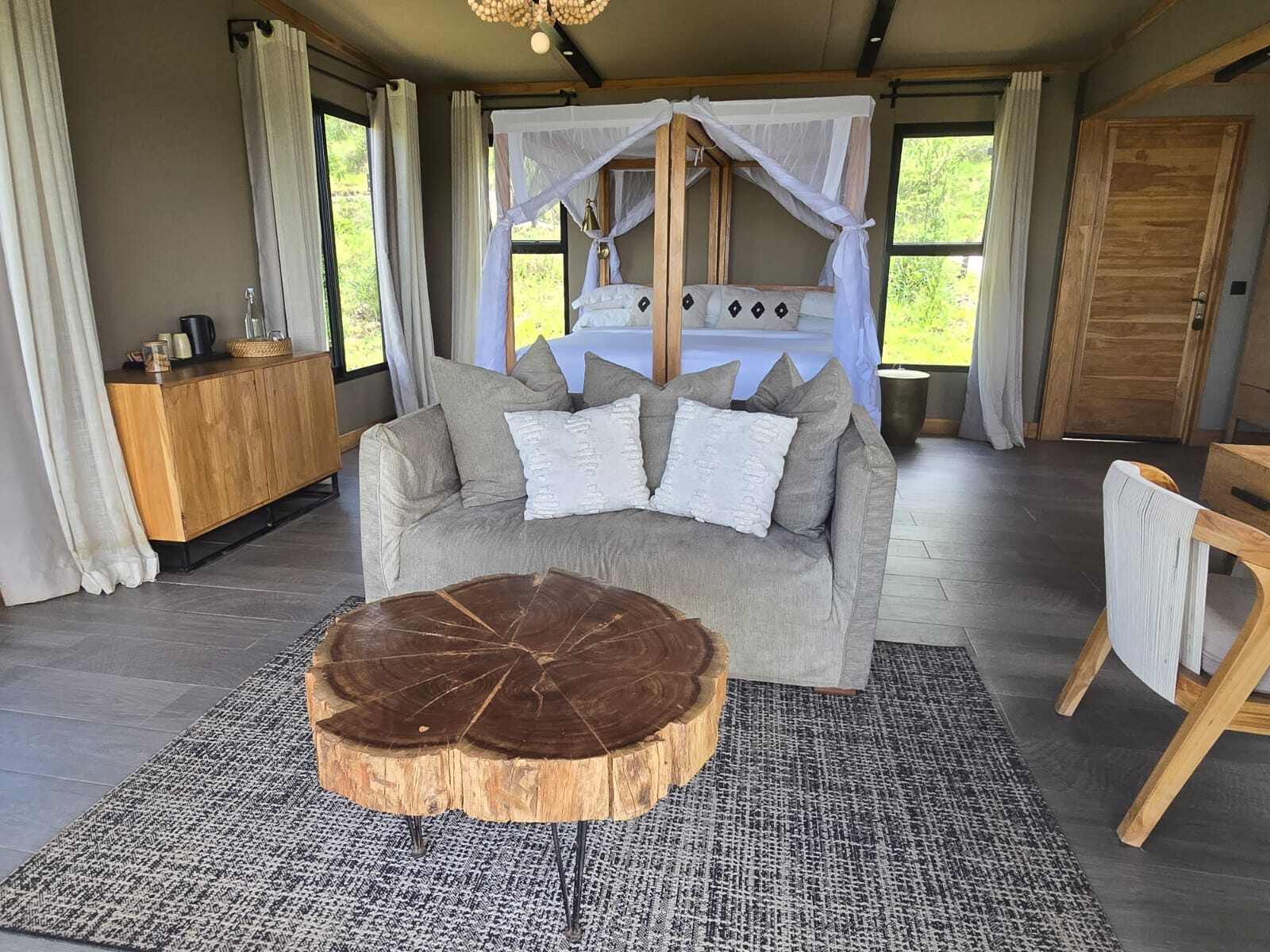 Gemütlich Lodge mit Himmelbett, Sofa und einer Baumstammscheibe als Tisch.