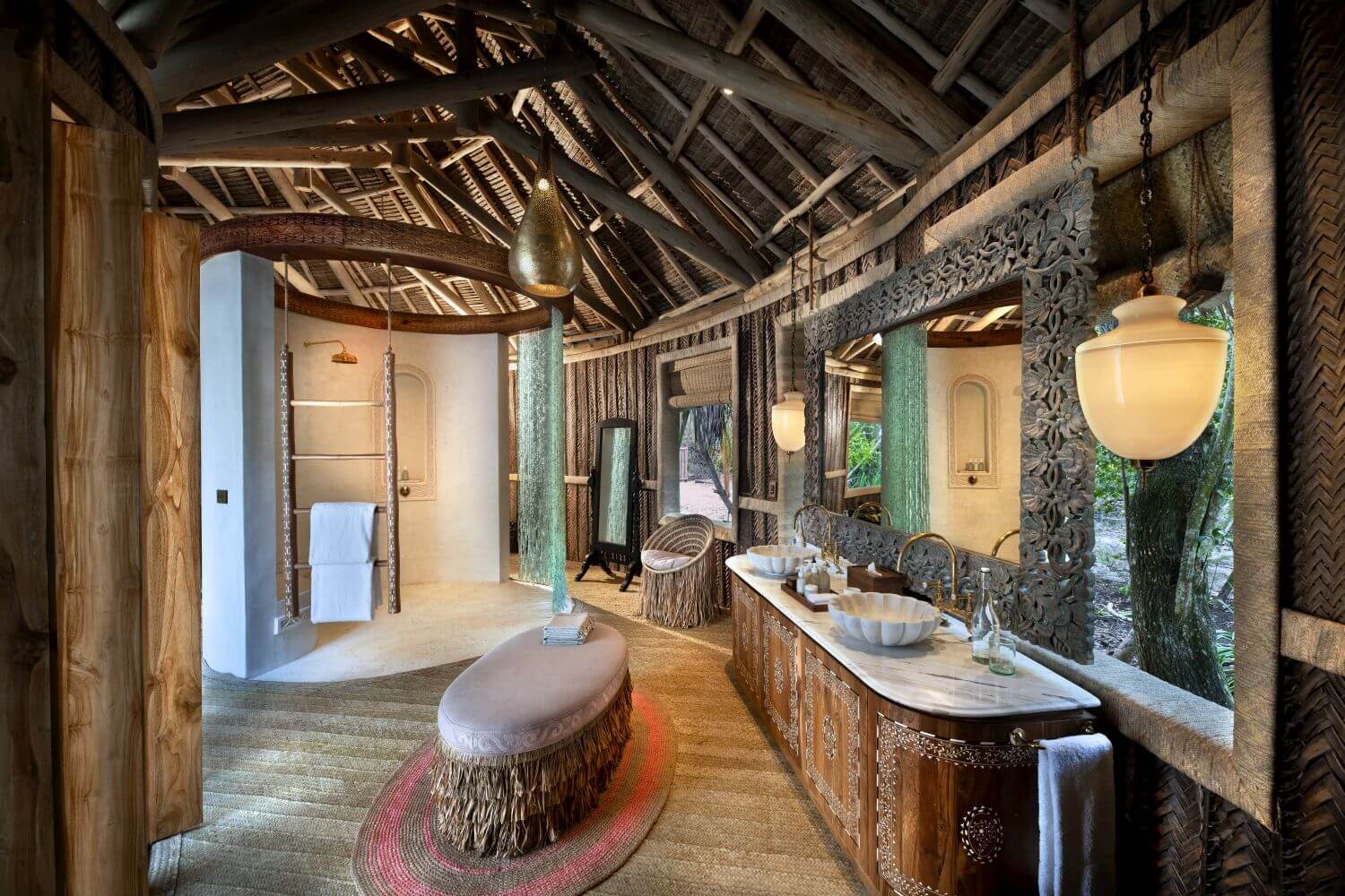Edles Badezimmer aus Naturmaterialien mit Dusche, Waschbecken und Bank in der Mitte.