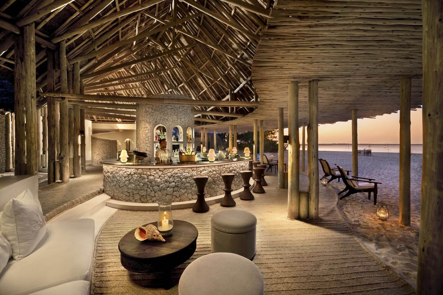 Bar im schicken Stil mit Holzdecke und gemauertem Tresen. Im Hintergrund sieht man das Meer.