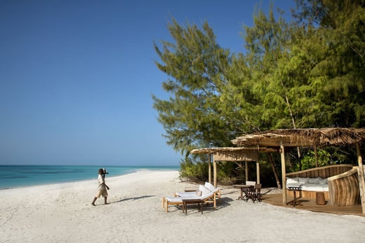Ein Servicemitarbeiter bringt Getränke zu einer Strandlounge.