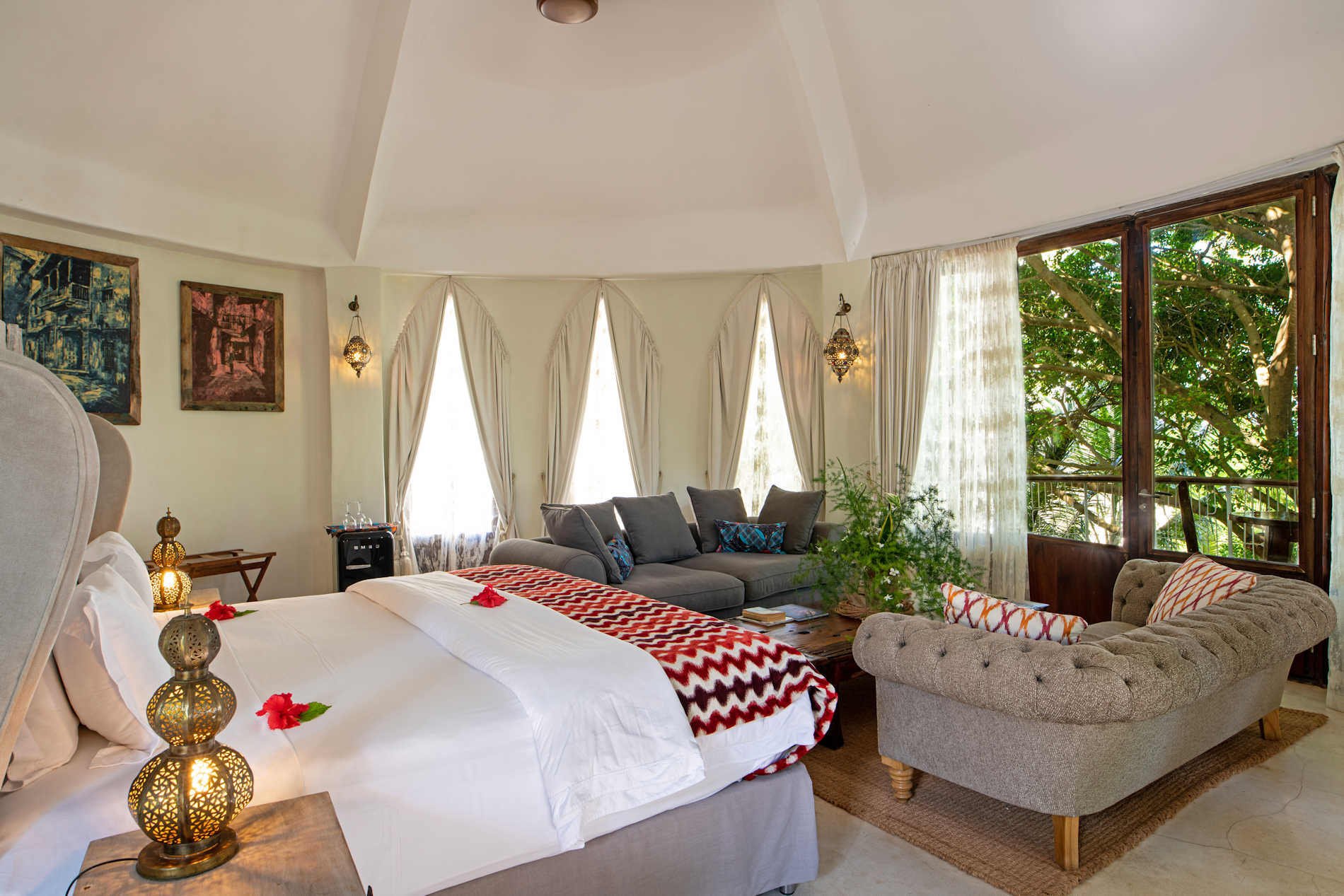 Inneneinrichtung einer Villa mit hoher Decke, Kingsize-Bett und Sitzmöbeln.