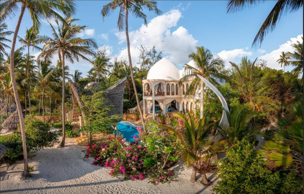 Gesamtblick auf eine Luxusvilla, die einem Garten voll Palmen und Pflanzen steht.