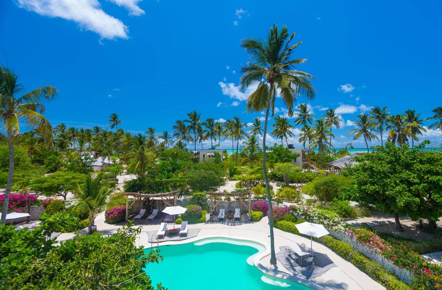Vogelperspektive auf das Resort mit Poollandschaft und üppiger Vegetation.