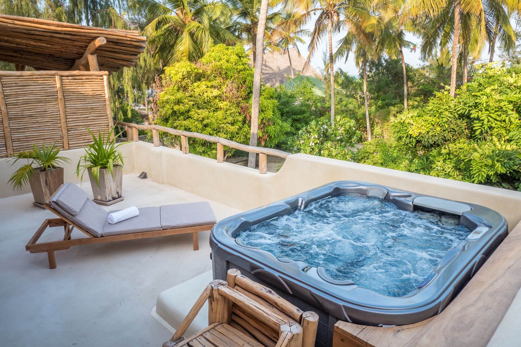 Auf einem Balkon steht ein Whirpool, daneben eine Liege.