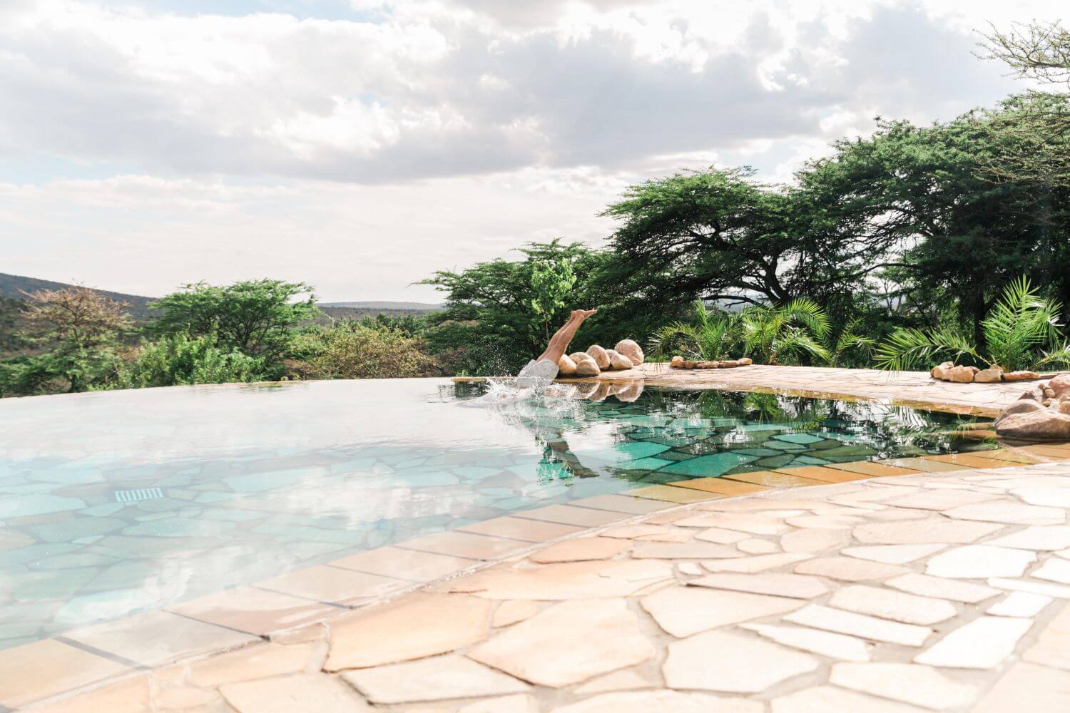 Swimmingpool umgeben von Naturfliesen mit Blick in die wilde Umgebung.