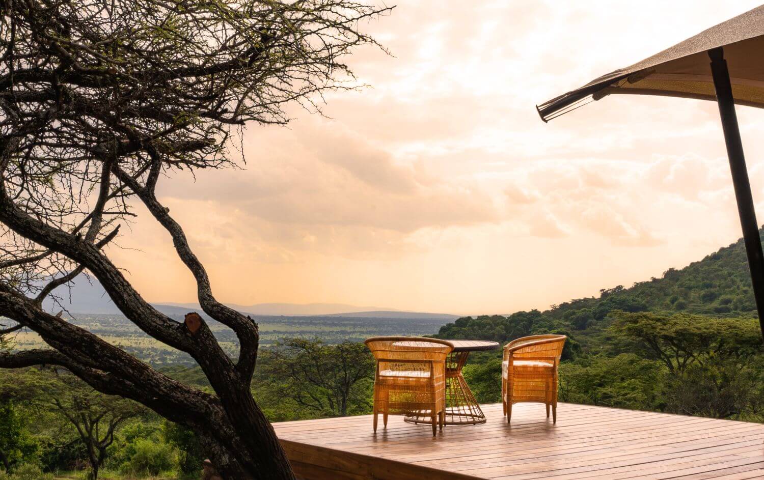 Auf einer Terrasse stehen zwei Stühle und ein Tisch. Der Blick in die Natur geht bis zum Horizont.