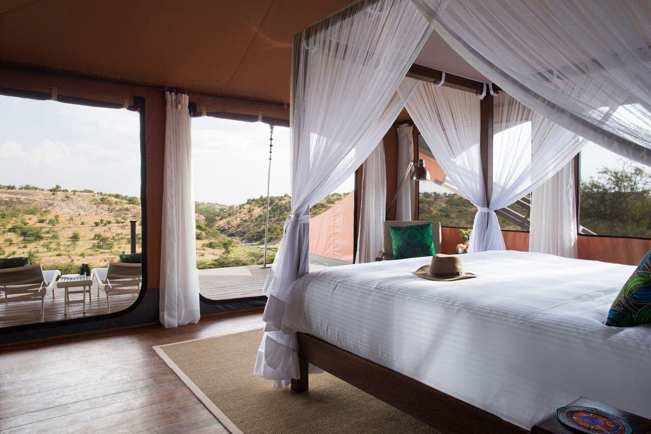 Geräumige Suite mit großem Himmelbett, das einen freien Blick in die Savanne bietet.