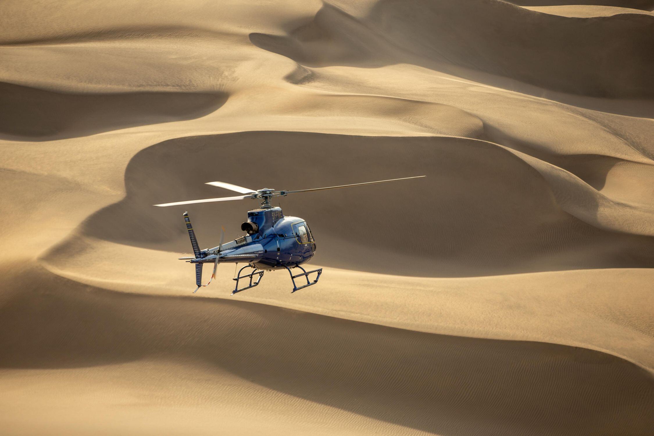 Ein Helikopter fliegt über eine Wüste.