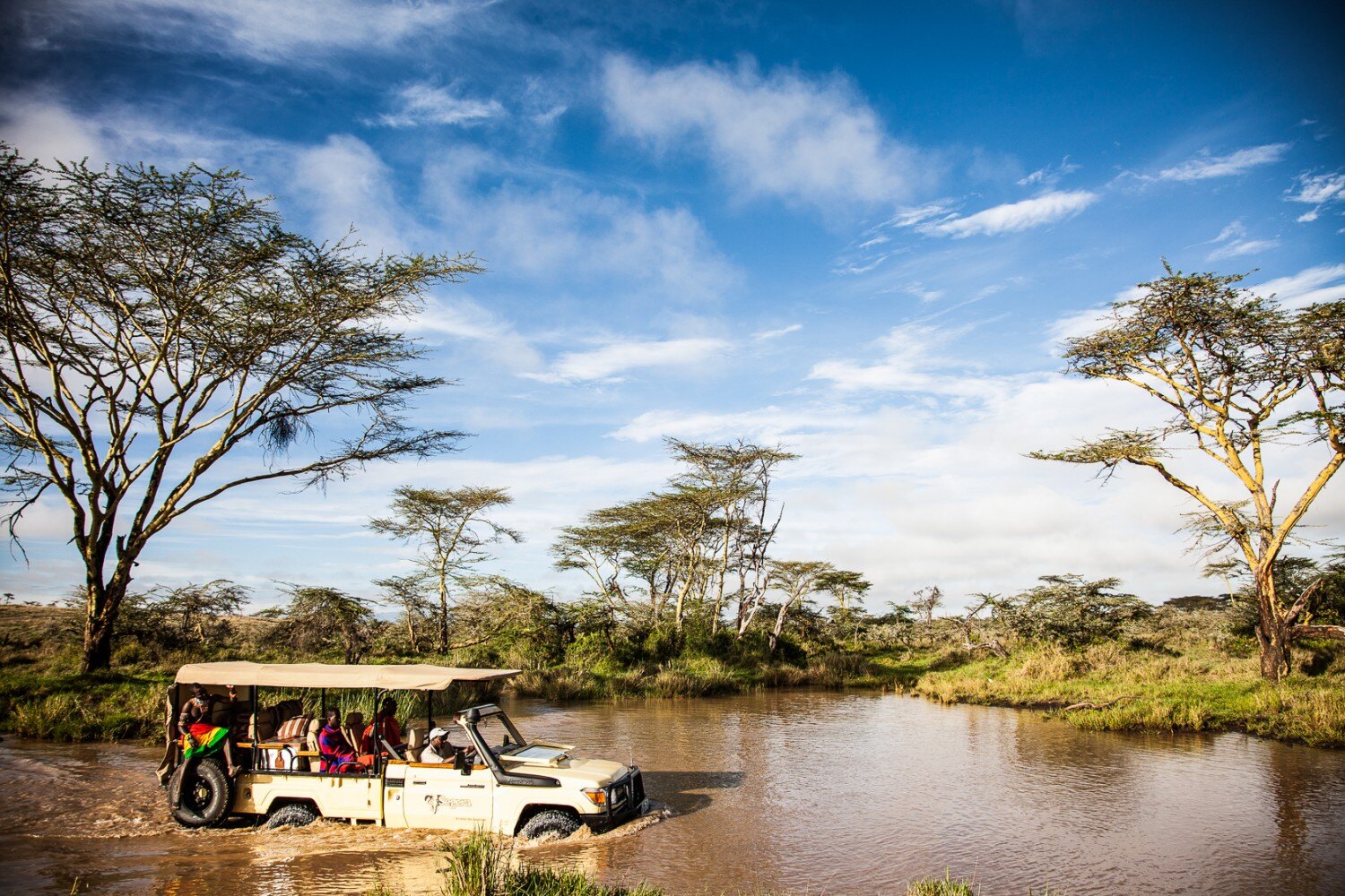 Ein Safarijeep durchquert einen Fluss.