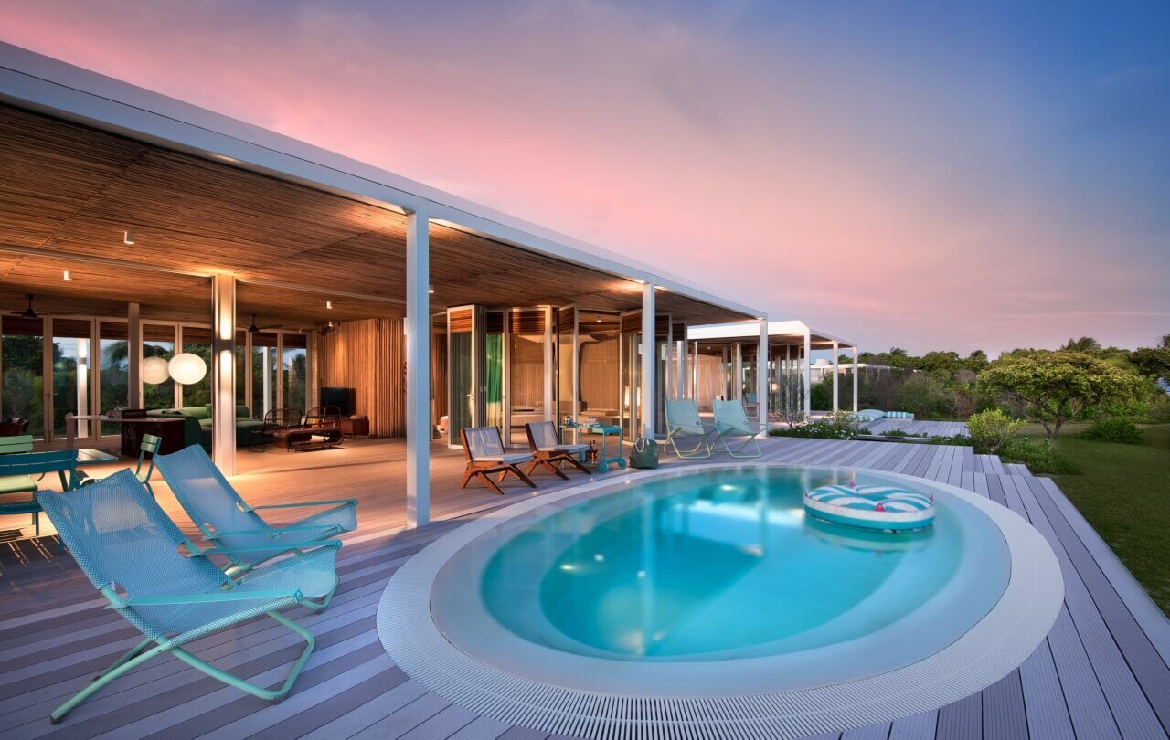 Beleuchtete Terrasse mit Pool und Liegen bei untergehender Sonne.