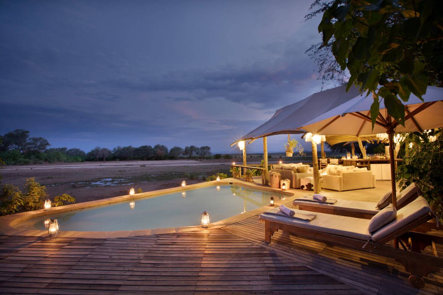 Beleuchteter Pool mit Sonnendeck in der Abenddämmerung.