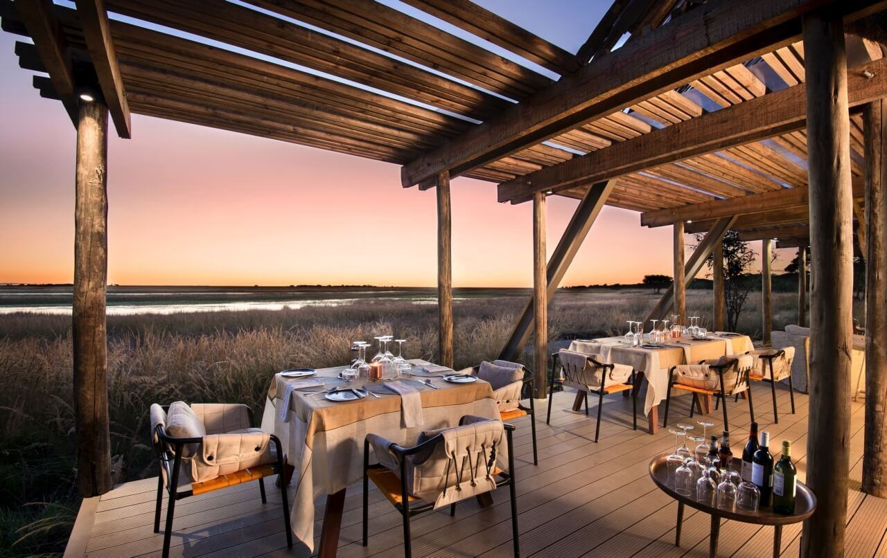 Restaurant auf einer Terrasse in der Abenddämmerung mit Blick in die Savanne.