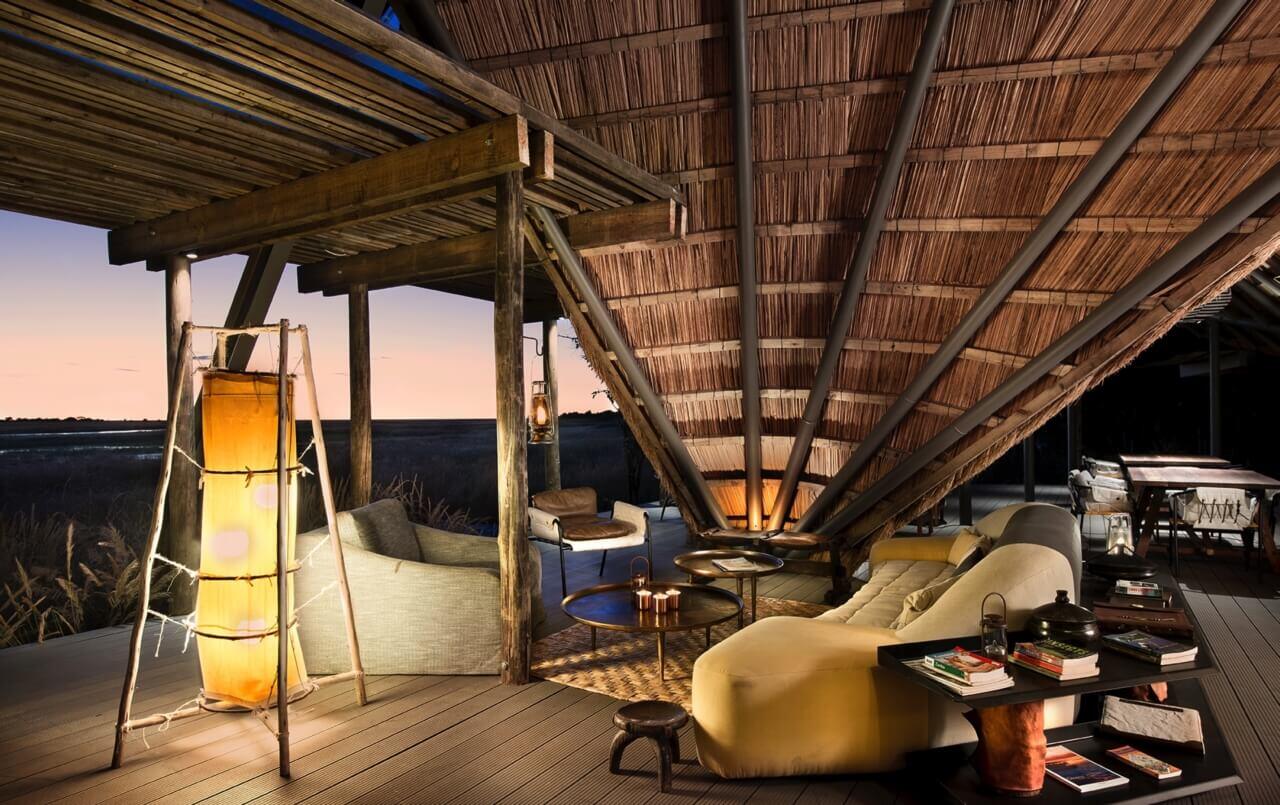 Lodge mit einem Strohdach, Sesseln und warmer Beleuchtung.
