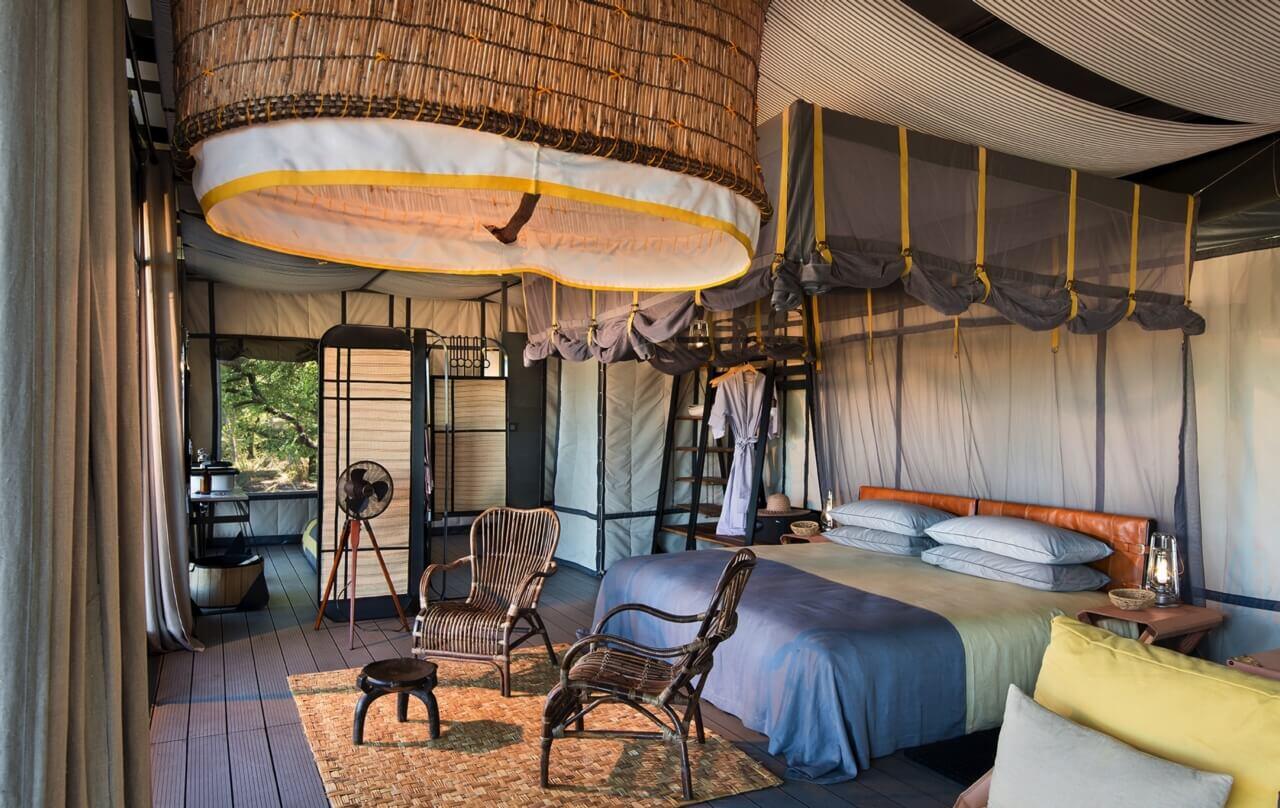 Luxuszelt mit Kingsize-Bett, Stühlen und Deckendeko.