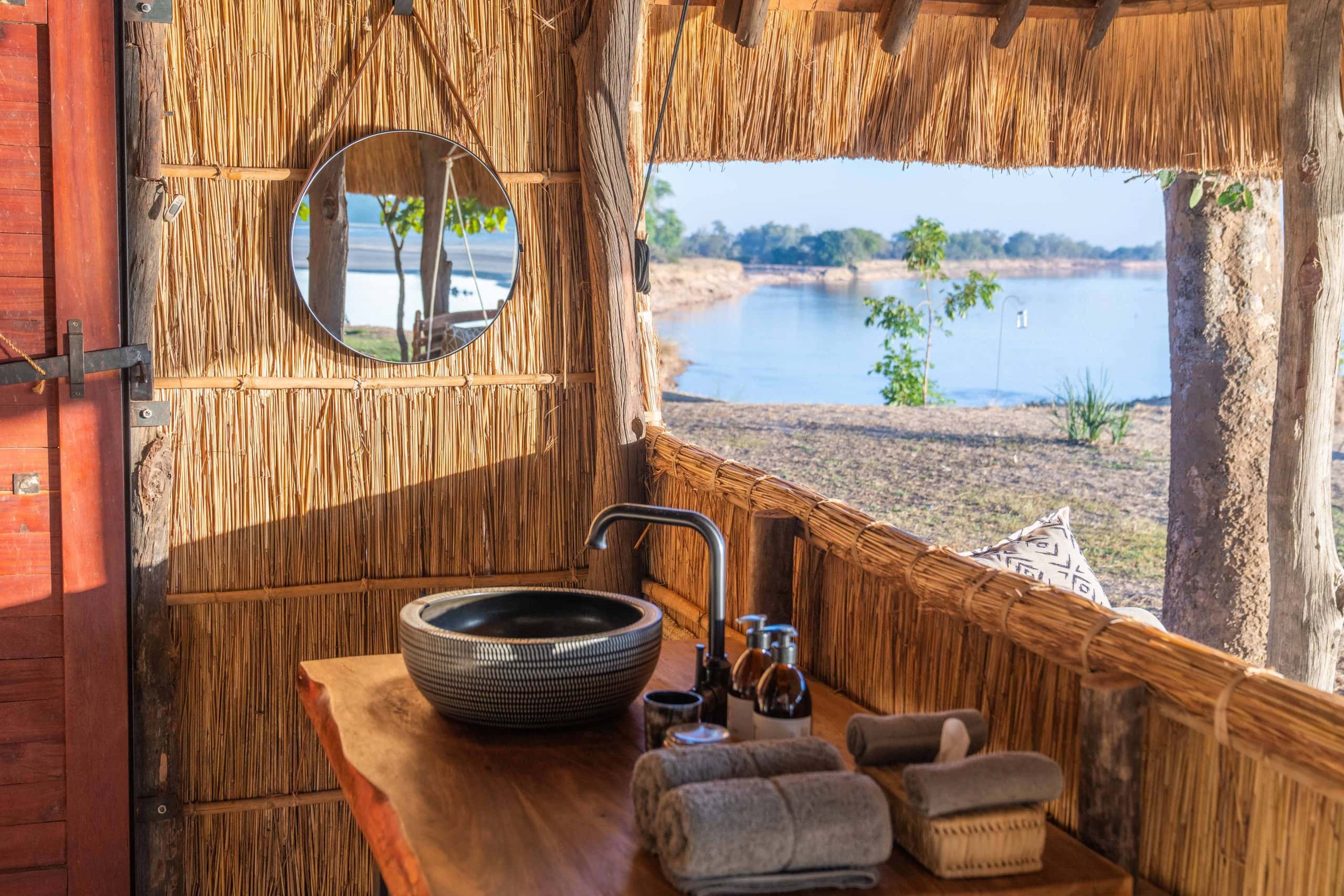 Freistehendes Waschbecken in einem Badezimmer aus Naturmaterialien mit Blick auf einen See.