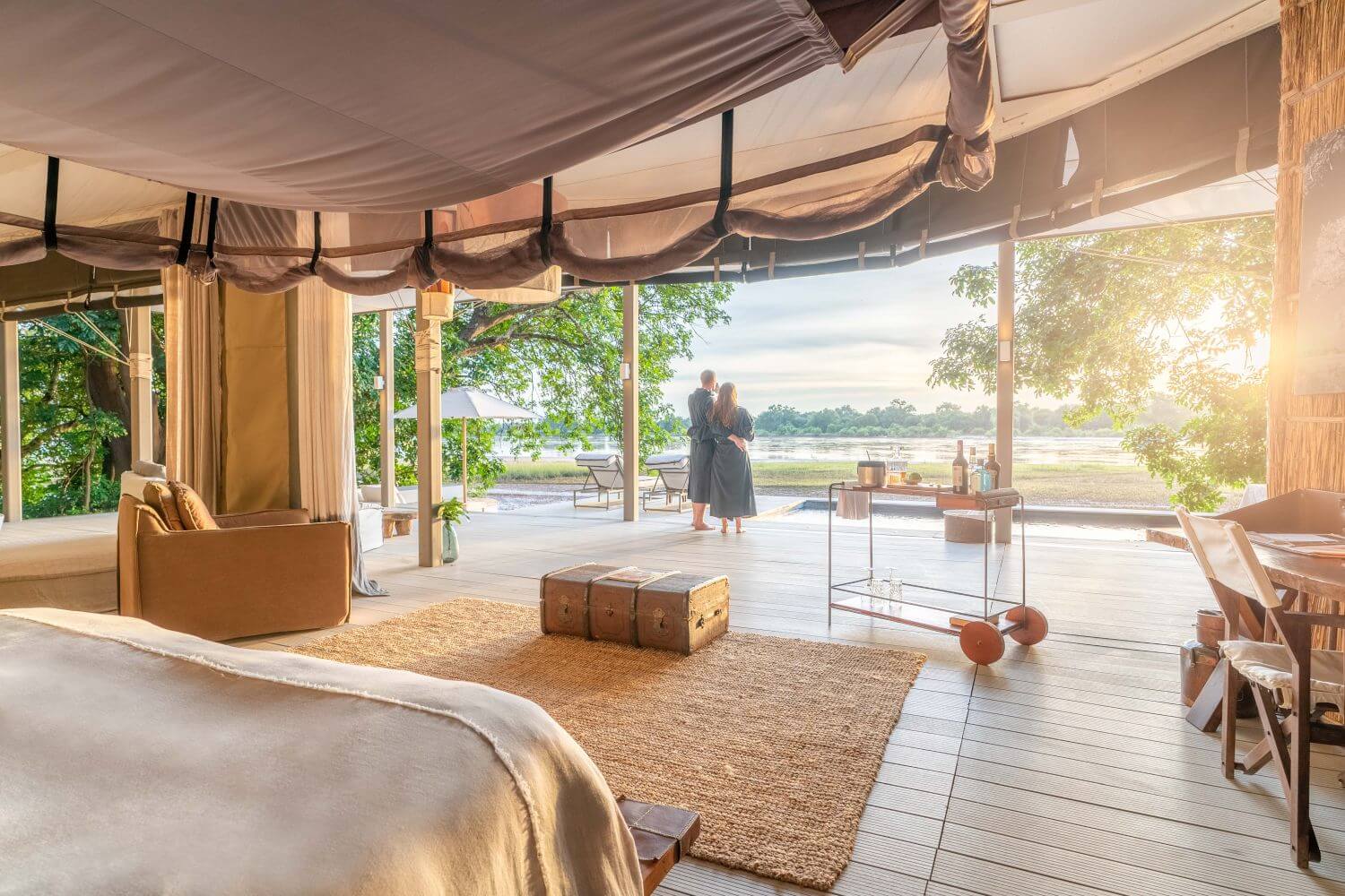 Blick von einer Luxussuite ins Freie. Ein Paar steht auf der Veranda und blickt in die Natur.