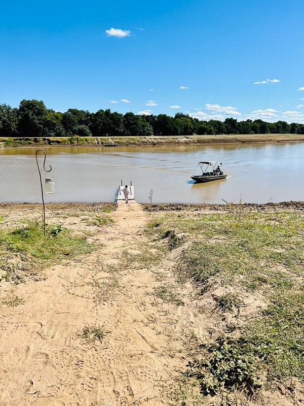 Sandpfad zu einem Boot auf einem Fluss in Sambia
