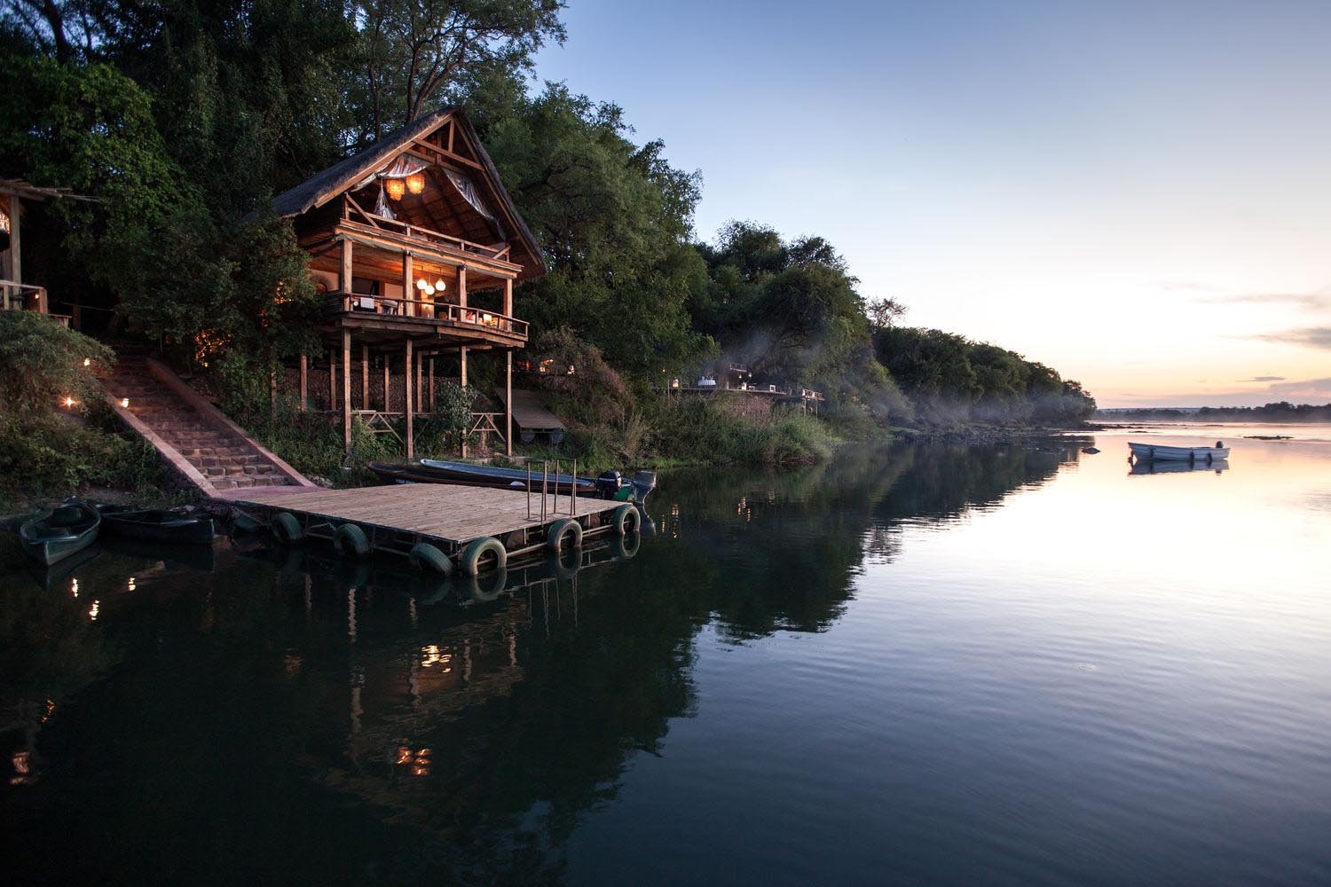 Lodge auf Stelzen an einem Fluss gelegen in der Abenddämmerung.