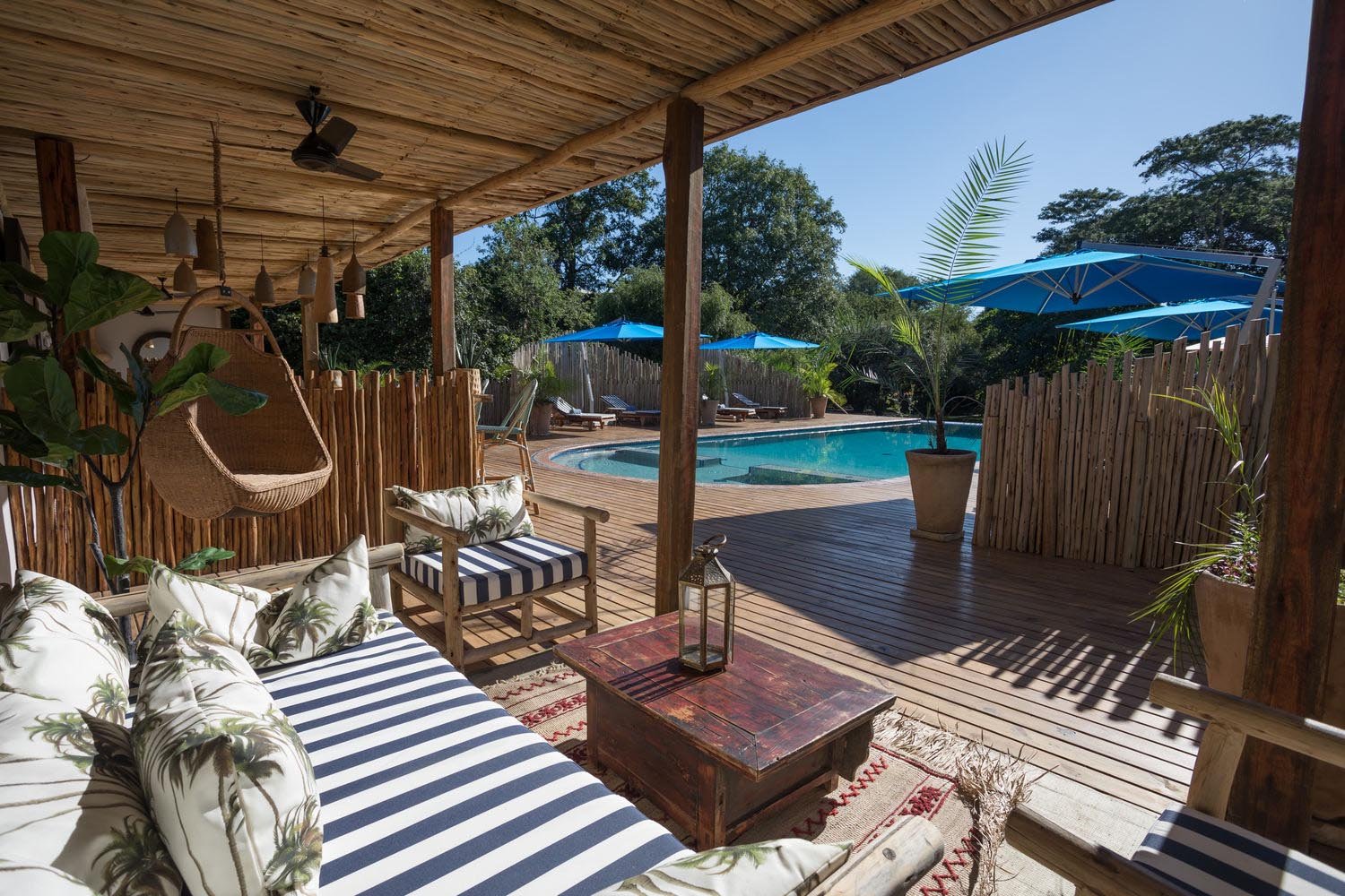 Sonnendeck mit gestreiften Sitzecken und einem Pool im Hintergrund.
