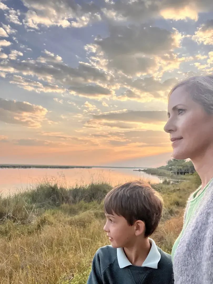 Mutter mit Sohn blicken bei Abendstimmung aufs Wasser.