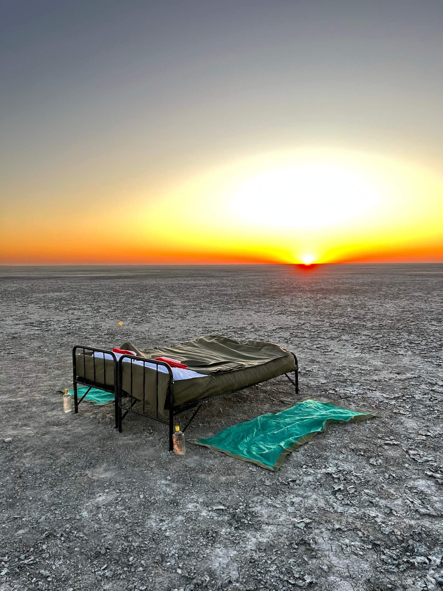 Ein Bett mitten in der weiten Makgadikgadi-Salzpfanne bei Sonnenuntergang.