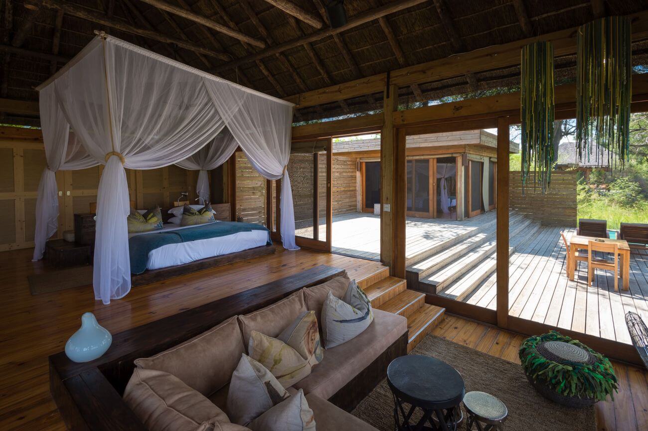 Geräumige Suite mit Bett und Sofa, im Hintergrund ist eine große Terrasse zu sehen.