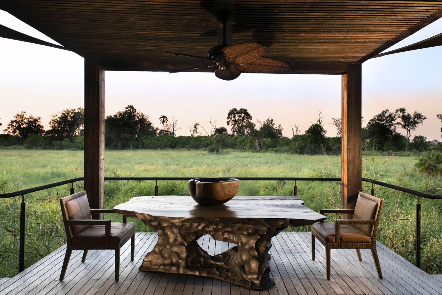 Terasse mit Tisch und Stühlen und Blick in die grüne Graslandschaft.