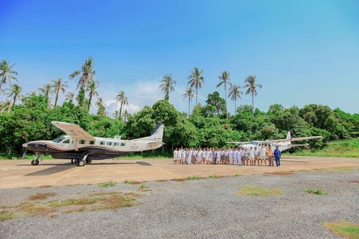 Eine Gruppe von Menschen steht auf  einer Landebahn in Thailand zwischen zwei Privatjets
