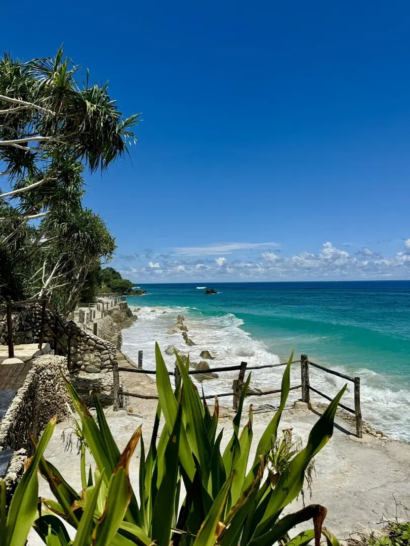 Traumstrand mit weißem Sand, blauem Wasser und üppiger Vegetation