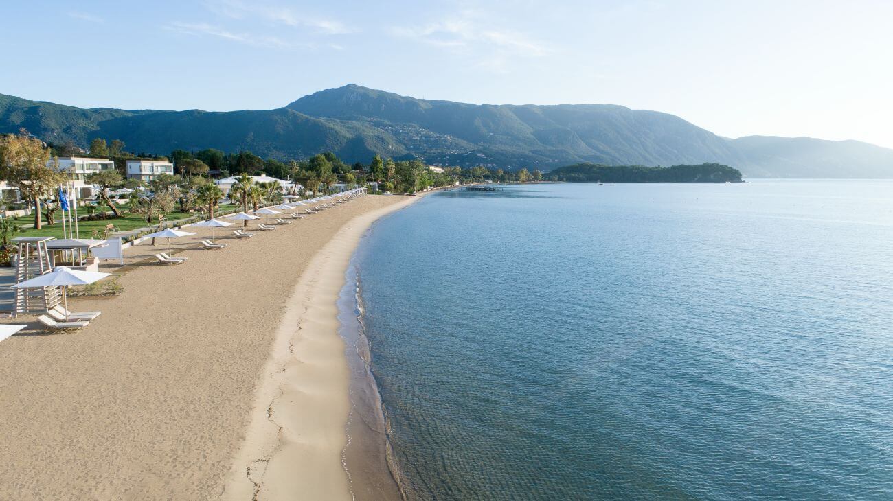 Kilometerlanger Sandstrand mit Bergen im Hintergrund.