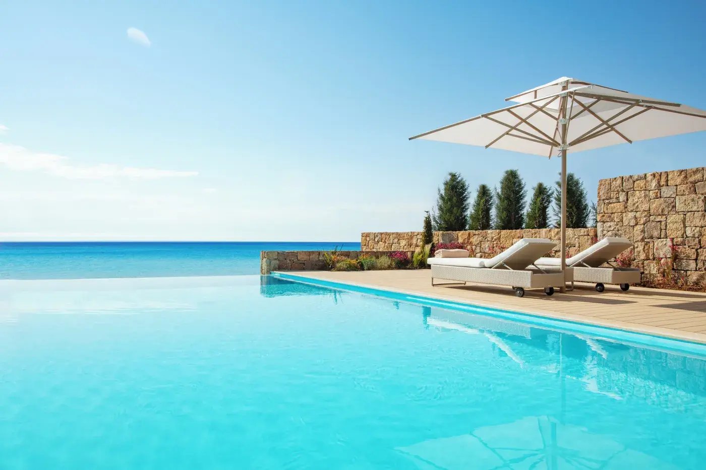 Infinity-Pool mit Liegen und Sonnenschirm.