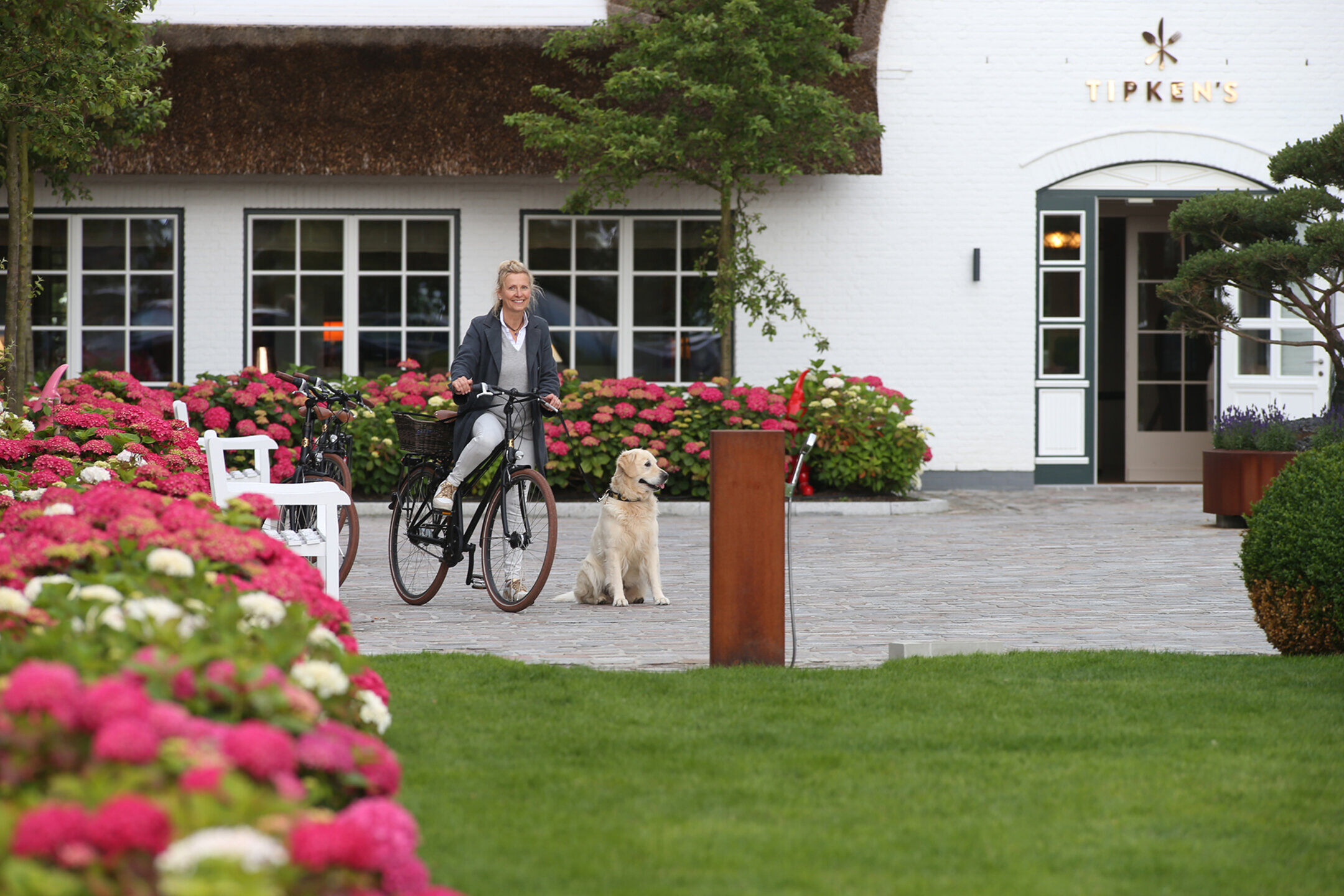 Frau mit Hund und Fahrrad vor dem Hotel Severins Sylt