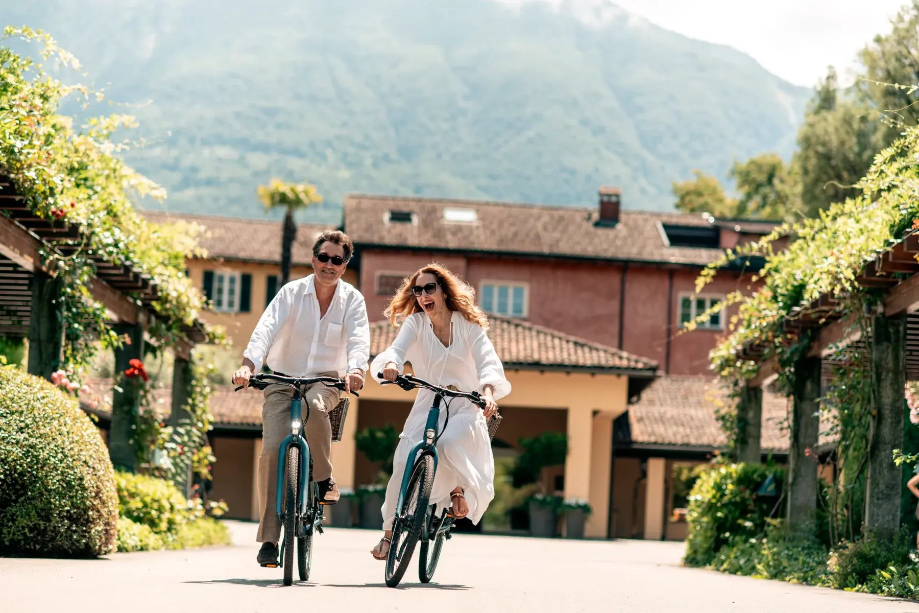 Ein Mann und eine Frau fahren mit dem Fahrrad von dem Innenhof eines Hotels.