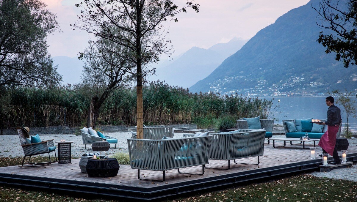 Ein Kellner bringt Getränke zu einer Lounge unter freiem Himmel am See.