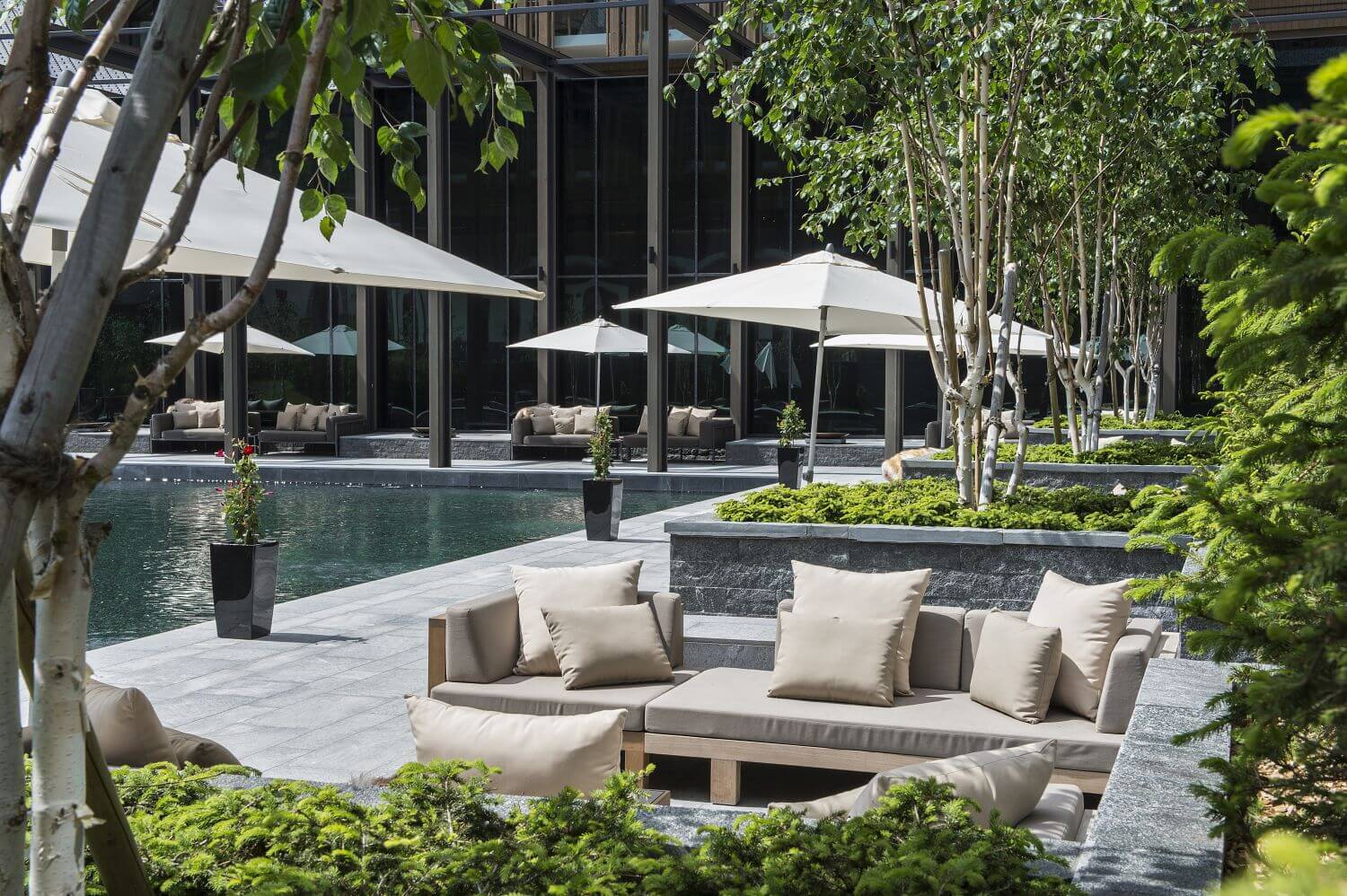 Poolbereich mit Chillout-Area und Sonnenschirmen.
