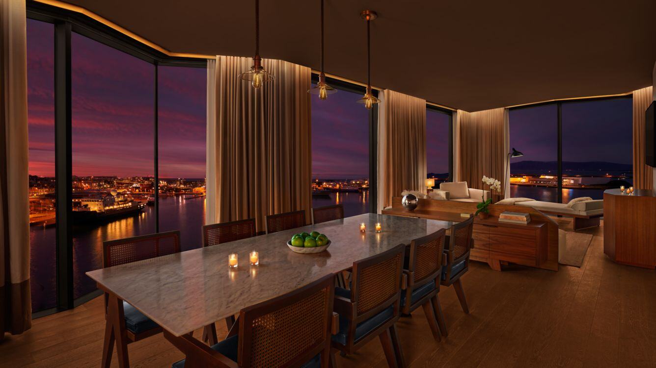 Cornersuite Essbereich und Wohnbeireich in Abendstimmung mit Infinity Fenster und Blick auf die leuchtende Stadt 