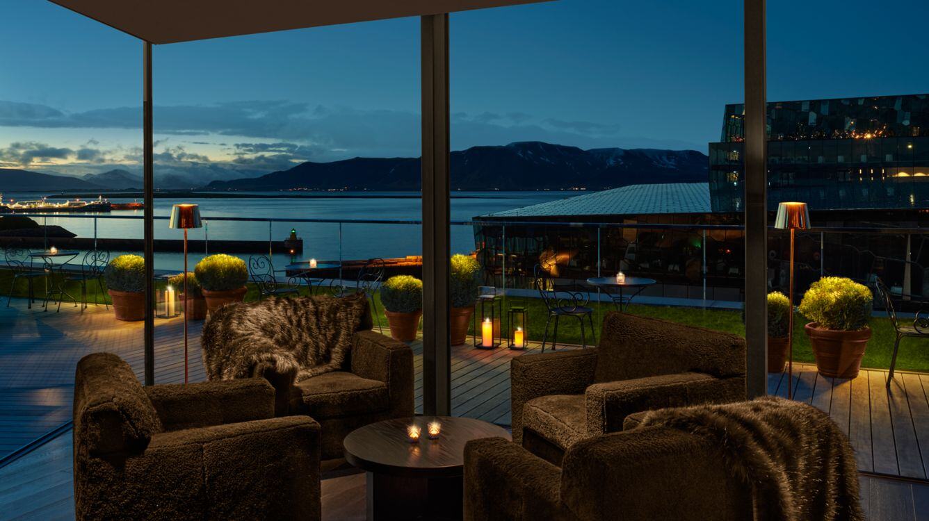 Sitzecke des Hotels bei gemütlicher Abendstimmung und Infinityfenster, Ausblick auf die Landschaft