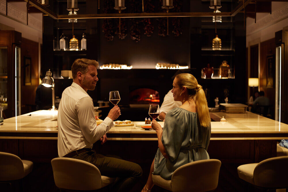 Ein Mann und eine Frau sitzen an einer Bar und trinken Wein.
