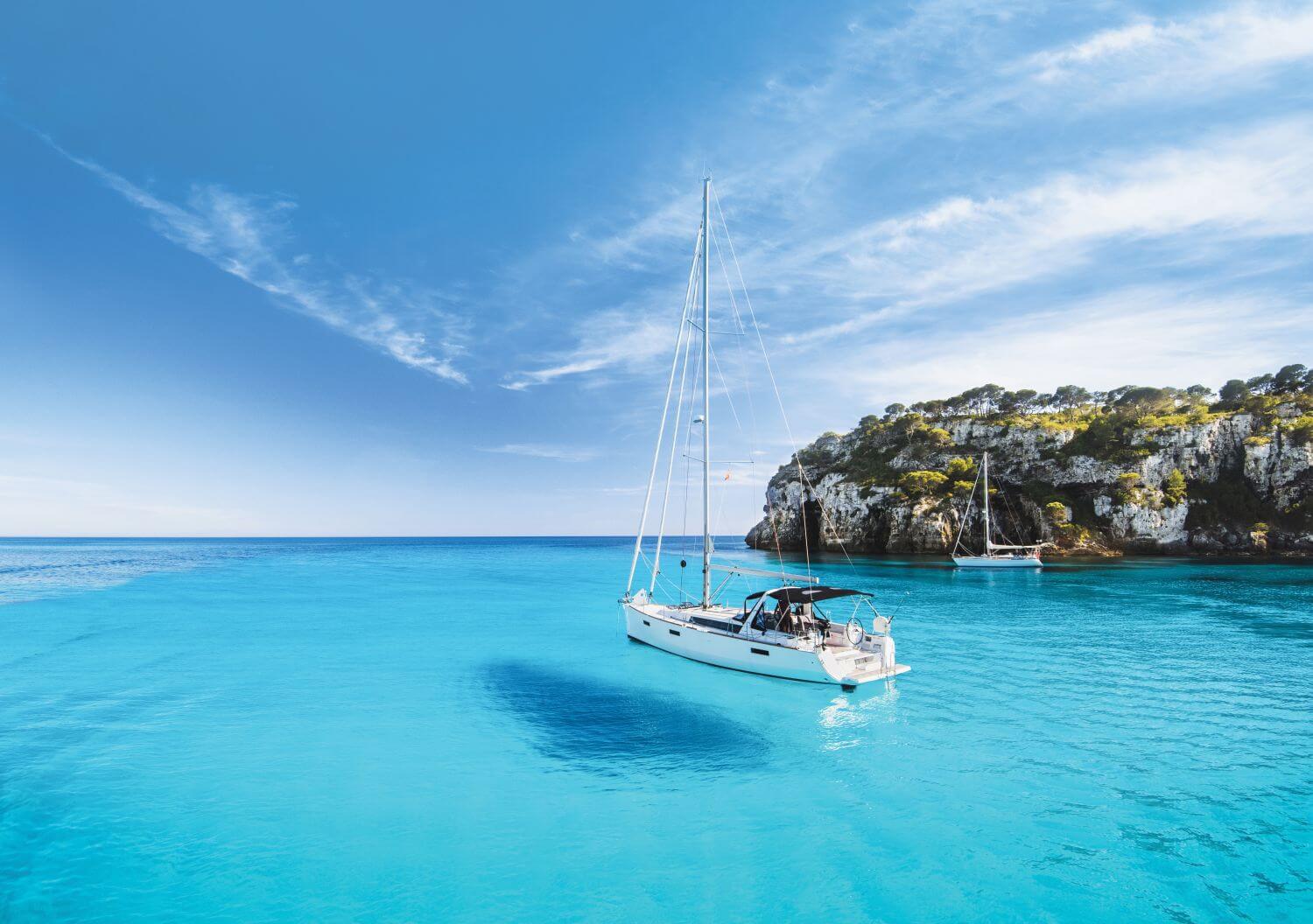 Segelyacht in einer Bucht, das Wasser ist so klar, es sieht aus, als ob sie schwebt.