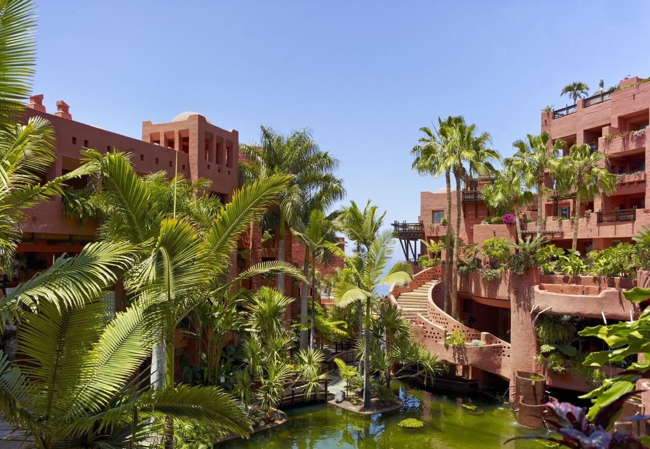 Hotelanlage mit Palmen und kleinem Teich.