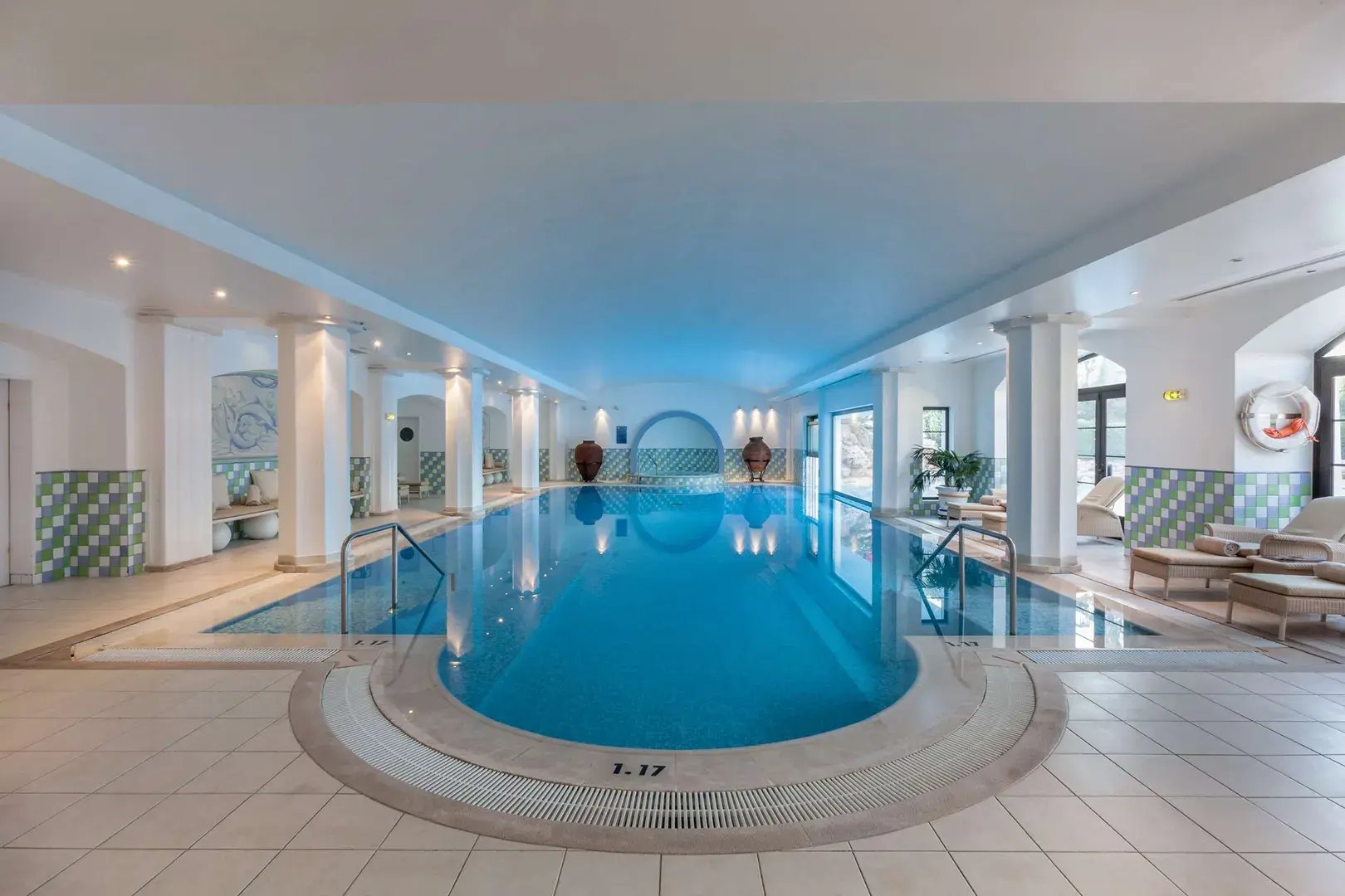 Edler Indoor-Pool mit Liegen am Rand.