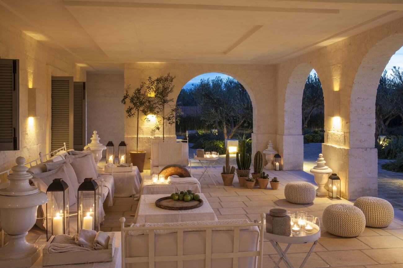 Beleuchtete Loggia einer Villa mit vielen Sitzmöglichkeiten.