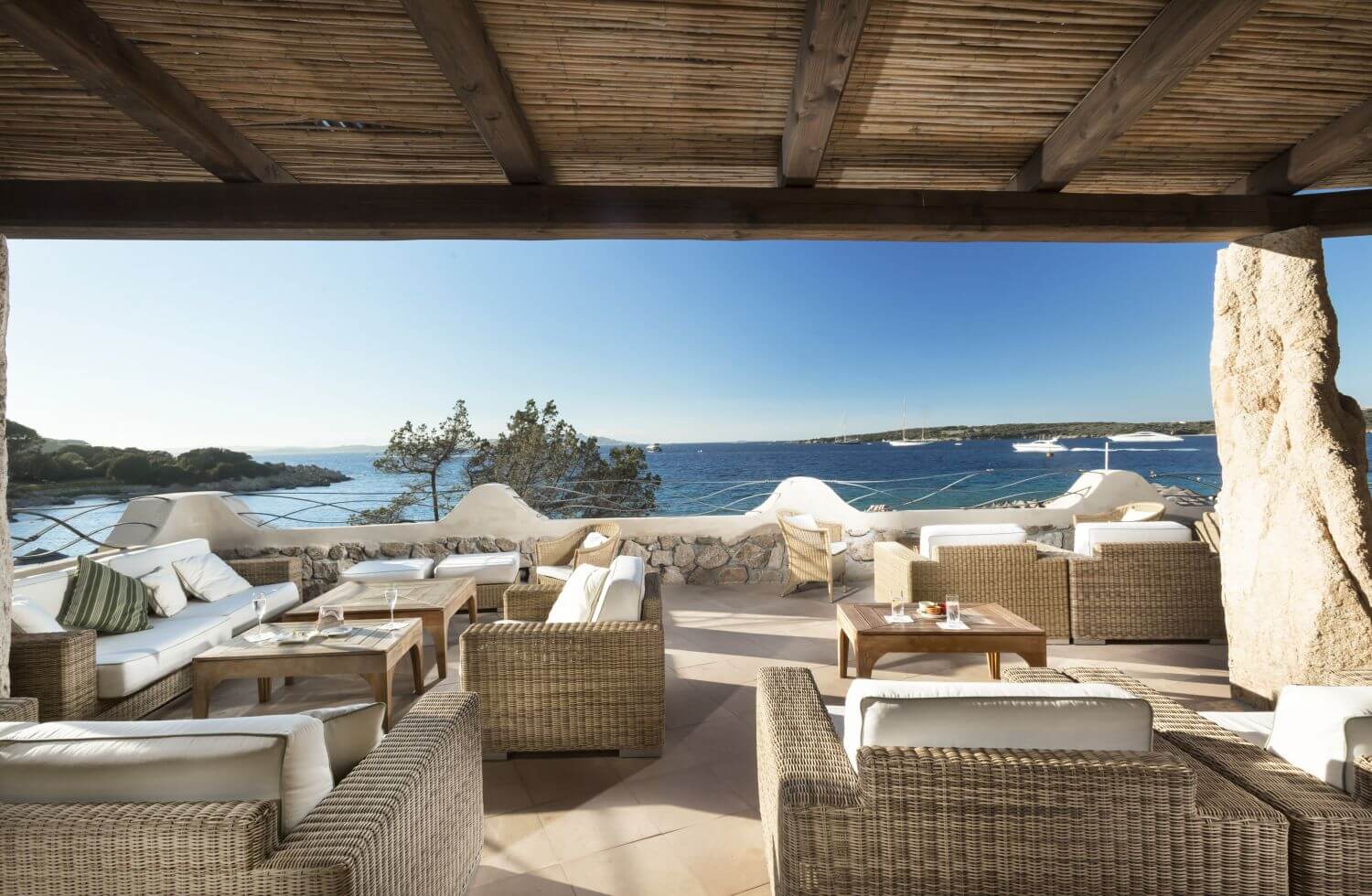 Café-Bar mit weißen, bequemen Möbeln und Sonnenschein sowie Blick auf das Meer