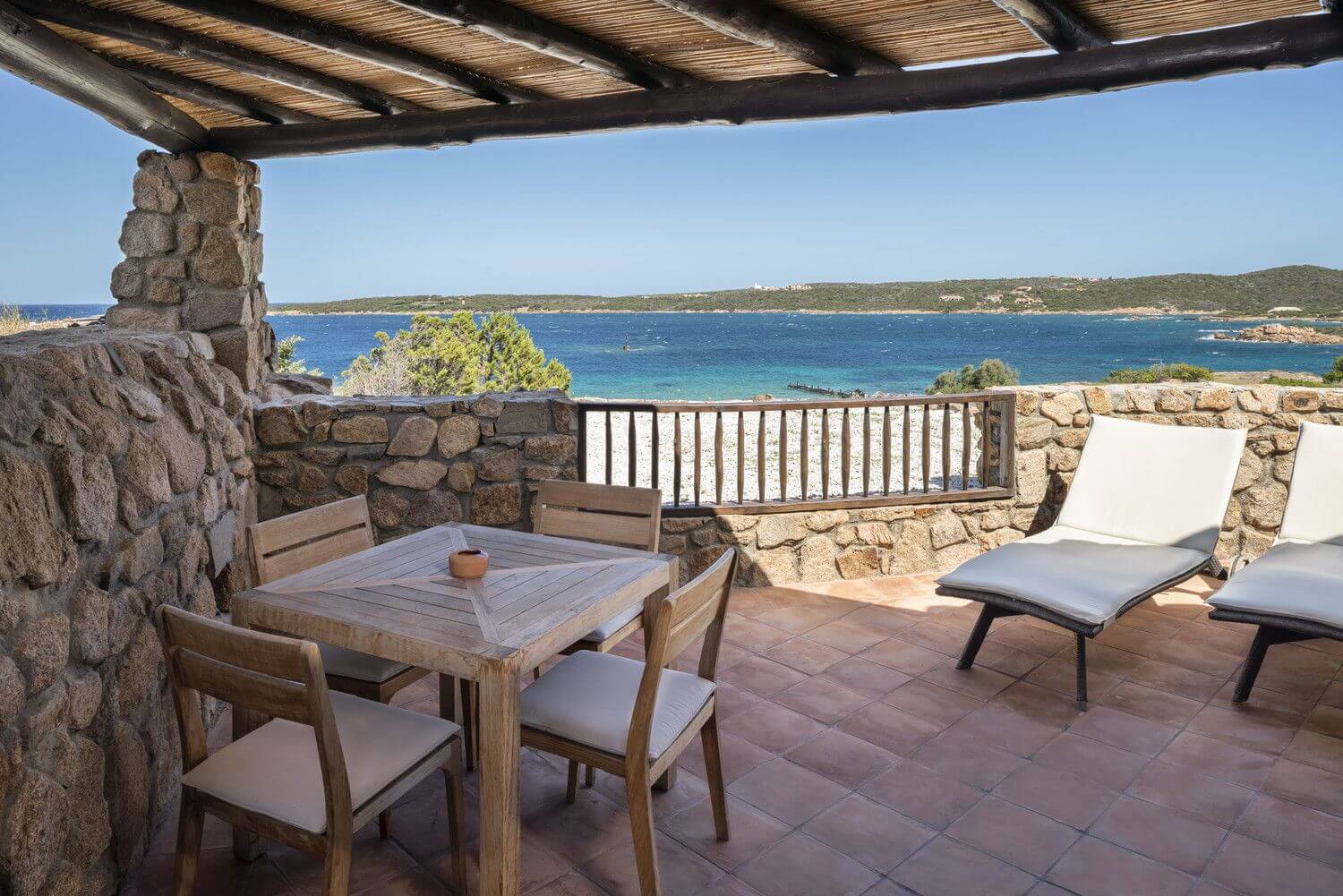 Private Sitzecke auf einer Terrasse mit Liegen und Blick auf das Meer.