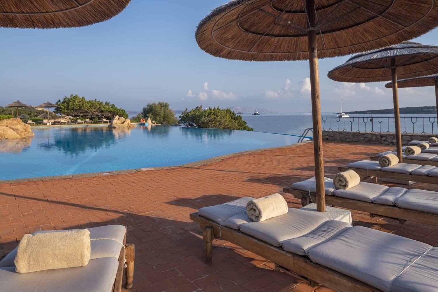 Infinity-Pool mit Liegen und Sonnenschirmen.