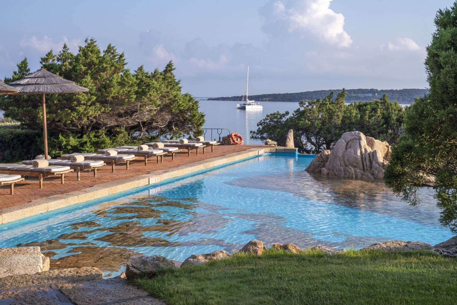 Pool Naturelementen und Liegen am Rand, umgeben von Grün.