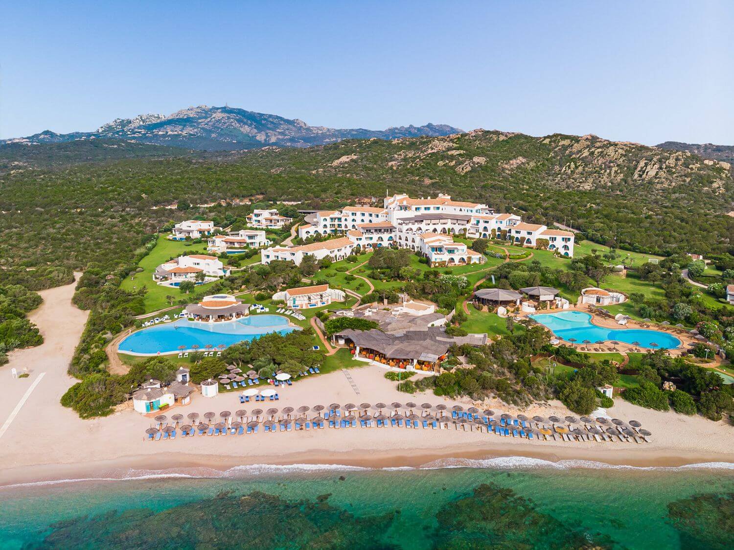 Hotelanlage aus der Vogelperspektive mit der umgebenden Landschaft Strand und Berge.