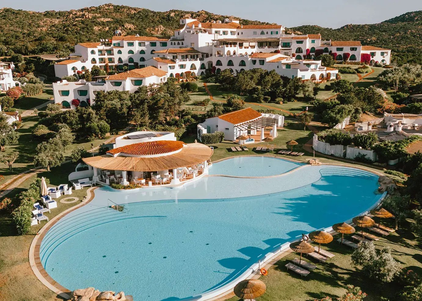 Hotelanlage mit Pool, die sich an einem Hang herunterschlägelt.